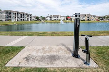 A pump in front of a pond with houses in the background